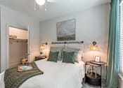Thumbnail 30 of 46 - A bedroom with a large bed, a nightstand with a lamp, and a painting on the wall.