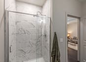Thumbnail 32 of 46 - A bathroom with a marble tile shower and a green towel hanging on the door.