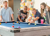 Thumbnail 8 of 31 - Four people playing pool in a room with balloons.