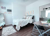 Thumbnail 29 of 31 - A bedroom with a white bed and a wooden desk.