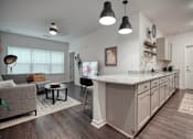 Thumbnail 22 of 31 - A modern kitchen with a large island and pendant lights.