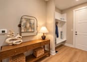 Thumbnail 3 of 29 - A hallway with a wooden bench and a lamp on it.