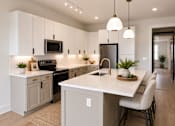 Thumbnail 5 of 5 - A modern kitchen with a white island and a black refrigerator.