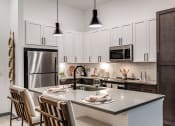 Thumbnail 15 of 47 - an open kitchen with a center island and a stainless steel refrigerator
