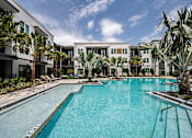 Thumbnail 37 of 40 - A swimming pool in front of a building with palm trees.