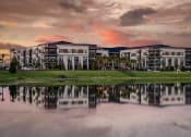 Thumbnail 47 of 47 - a view of an apartment building reflected in a lake at sunset