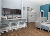 Thumbnail 6 of 30 - a common room with a kitchenette and couches