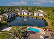 Thumbnail 43 of 49 - A large swimming pool surrounded by a fence and a small lake in the middle of a housing complex.