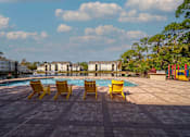 Thumbnail 30 of 49 - A pool area with yellow chairs and a red playground.