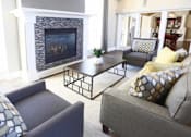 Thumbnail 9 of 20 - A living room with a fireplace and a grey couch.