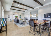 Thumbnail 4 of 22 - Downtown Greenville, SC Apartments - The Aster - Resident Clubroom with High Ceilings, Vinyl Plank Flooring, Area Rug, Mounted Television, Seating Area, Table, and Chairs.
