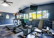 Thumbnail 4 of 26 - A gym with a variety of equipment including treadmills, exercise bikes, and a television at Coral Club Apartments in Bradenton, FL