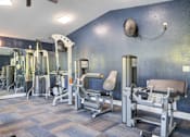 Thumbnail 3 of 26 - A gym with a variety of equipment including a leg press machine, a chest press machine, and a squat rack at Coral Club Apartments in Bradenton, FL