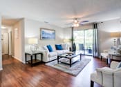 Thumbnail 8 of 26 - A living room with a white couch and a painting on the wall at Coral Club Apartments in Bradenton, FL
