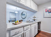 Thumbnail 5 of 26 - A kitchen with white cabinets and a wooden cutting board on the counter at Coral Club Apartments in Bradenton, FL
