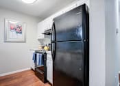 Thumbnail 6 of 26 - A black refrigerator in a kitchen with a picture on the wall at Coral Club Apartments in Bradenton, FL