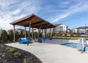 Thumbnail 17 of 22 - a canopy over a playground with a pool and chairs
