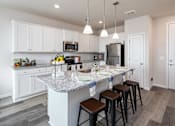 Thumbnail 1 of 28 - A kitchen with a granite countertop and bar stools.