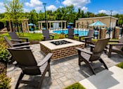 Thumbnail 30 of 35 - A patio with a fire pit and chairs.