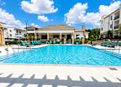 Thumbnail 1 of 35 - A large swimming pool with sun loungers and a building in the background.