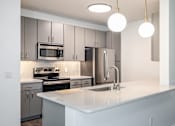 Thumbnail 4 of 35 - A modern kitchen with a white countertop and stainless steel appliances.
