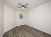 Thumbnail 18 of 35 - A room with a ceiling fan and wooden flooring.