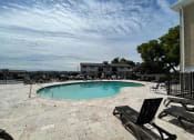 Thumbnail 27 of 41 - Apartments for Rent in Chattanooga, TN - Riverview North - Shimmering Pool with Expansive Sundeck, Lounge Seats, Black Chairs, and Tiled Flooring.