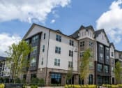 Thumbnail 54 of 56 - a large apartment building with a cloudy blue sky in the background