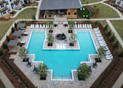 Thumbnail 24 of 28 - A large swimming pool surrounded by a stone patio and a small fire pit.