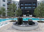 Thumbnail 22 of 28 - A black building with a pool and a fountain in front.