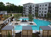 Thumbnail 21 of 28 - A large swimming pool surrounded by lounge chairs and trees.