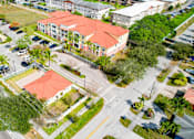 Thumbnail 13 of 15 - A parking lot with cars and a building with a red roof.