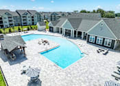 Thumbnail 37 of 48 - A large swimming pool surrounded by a patio and a building in the background.