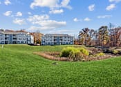 Thumbnail 12 of 13 - A grassy field with a building in the background.