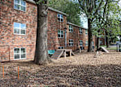 Thumbnail 19 of 24 - A playground area in front of a brick building.
