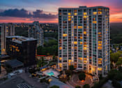 Thumbnail 72 of 72 - A tall building with a pool in front of it is lit up at dusk.