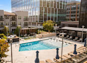 Thumbnail 49 of 72 - A swimming pool surrounded by a patio with chairs and umbrellas.