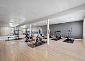 Thumbnail 22 of 28 - A spacious gym with a variety of equipment including treadmills, stationary bikes, and weight machines.