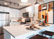 Thumbnail 3 of 31 - a kitchen with a white counter top and a stainless steel refrigerator