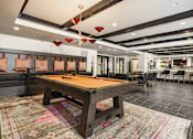 Thumbnail 10 of 45 - A pool table in a room with a high ceiling and a rug on the floor.