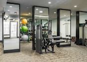 Thumbnail 15 of 45 - A gym with a variety of equipment including a squat rack, bench, and exercise balls.