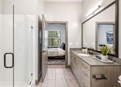 Thumbnail 16 of 43 - A bathroom with a glass shower door and a wooden vanity.