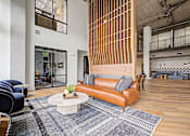 Thumbnail 34 of 43 - A modern living room with a brown leather couch and a white coffee table.