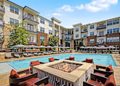 Thumbnail 23 of 43 - A large outdoor pool surrounded by a fire pit and lounge chairs.