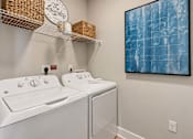 Thumbnail 8 of 29 - A laundry room with a washer and dryer and a painting on the wall.
