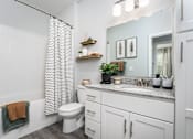 Thumbnail 10 of 21 - Pet-Friendly Apartments in Alexandria, KY - Elevation Apartment Homes - Bathroom With White Cabinetry, Granite Countertop, Large Mirror, Patterned Shower Curtain, And Modern Vanity Lighting.