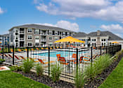 Thumbnail 31 of 35 - A pool surrounded by a black fence with a yellow umbrella.