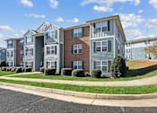 Thumbnail 11 of 13 - A row of townhouses with a sidewalk and green bushes in front.