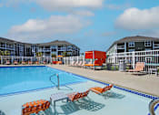 Thumbnail 24 of 31 - A swimming pool with orange chairs and a red object in the background.