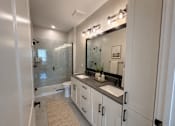 Thumbnail 8 of 11 - A bathroom with a sink, mirror, and shower.